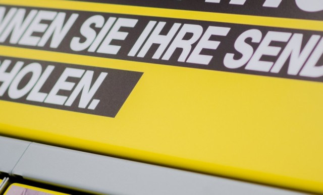 Gelbe Abholstation mit Aufschrift „Hier können Sie Ihre Sendung selbst abholen.“