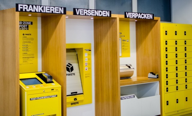 Selbstbedienungsbereich der Post mit Stationen zum Frankieren, Versenden und Verpacken.