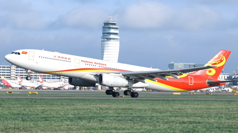 Hainan Airlines aircraft taking off in front of Vienna Airport's control tower.
