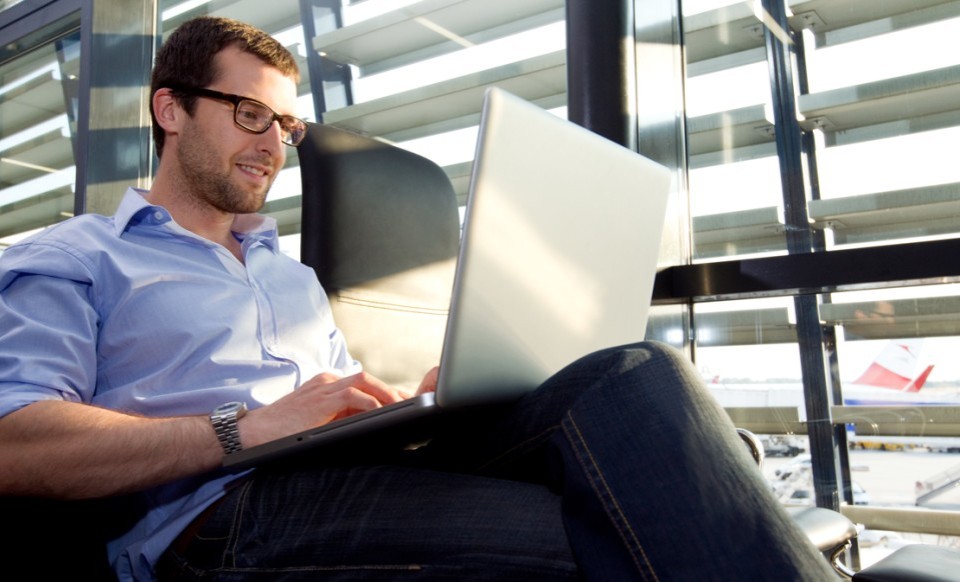 Ein Mann sitzt mit Laptop am Schoß in einem bequemen Sitz.