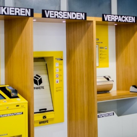 Postal self-service area with stations for stamping, shipping, and packaging.